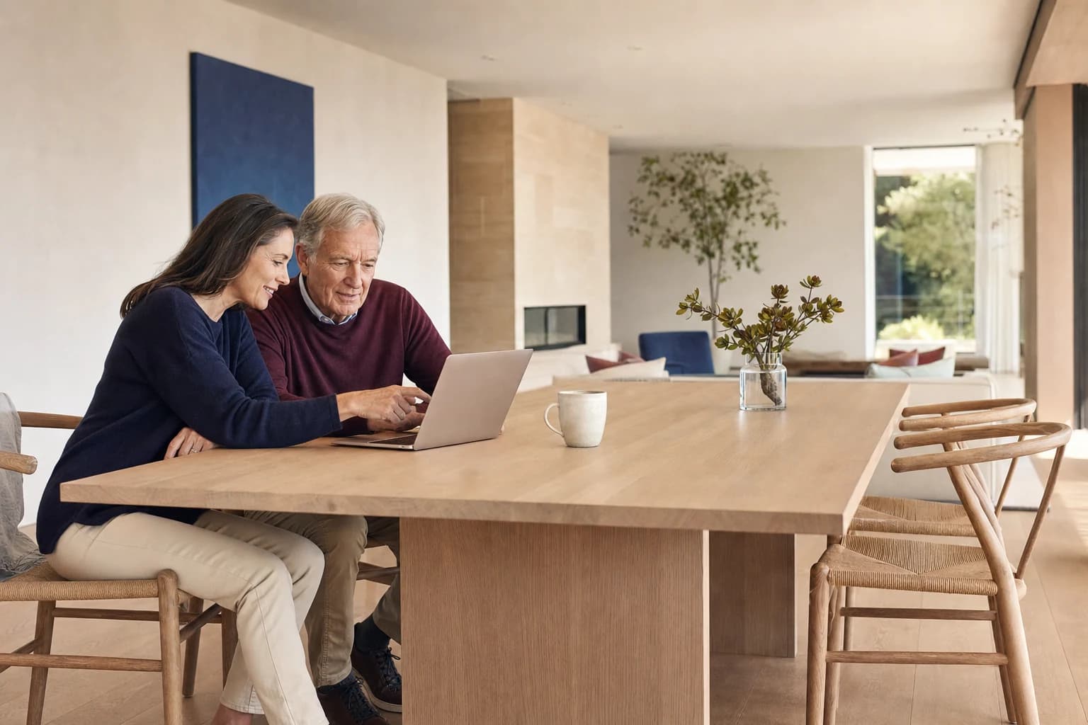 An adult daughter and her father looking together at the Silver Dollar app on a laptop at a sunlit kitchen table